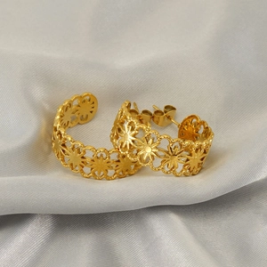 Golden stainless steel hoop earrings with hollow floral pattern on grey silk fabric