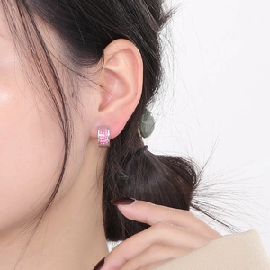 Close-up of a silver huggie hoop earring with pink stones worn by a professional model