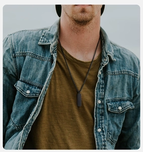Close-up of black rectangular military tag pendant necklace on a male model