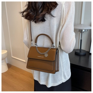 Brown leather crossbody bag detail with silver chain and white fashion text logo