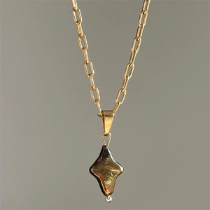 Golden chain necklace with iridescent baroque pearl cross pendant on grey background
