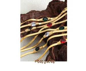 Detailed close-up of geometric gold snake chains with vibrant oval gemstones and zircons