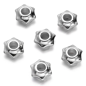 Macro view of six silver star-shaped spacer beads with metallic finish for jewelry making