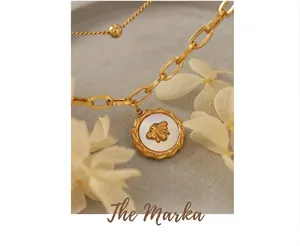 Makroaufnahme von Bienenanhänger mit Muscheleinlage an goldener Paperclip-Kette
