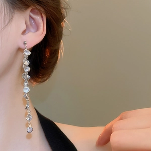 Close-up of long silver tassel earrings with round cubic zirconia and dangling fringe