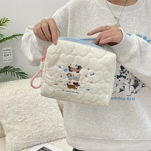 Detail of cream quilted makeup bag with heart texture and cartoon dog embroidery
