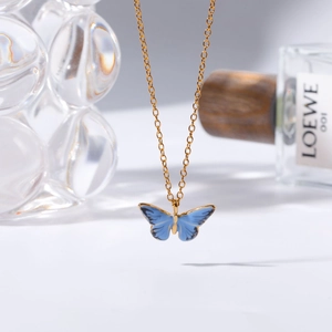 Détail d'un collier chaîne dorée avec un pendentif papillon en émail bleu éclatant