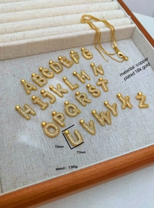 Macro view of 18K gold plated alphabet charms with shimmering micro-set zircon stones