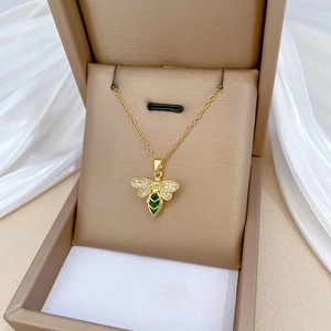 Golden bee necklace with green gemstone and crystals displayed in a brown gift box