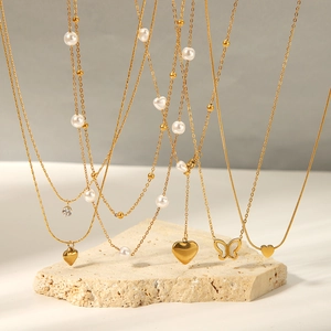 Colliers dorés avec pendentifs cœur et papillon ornés de perles sur une pierre