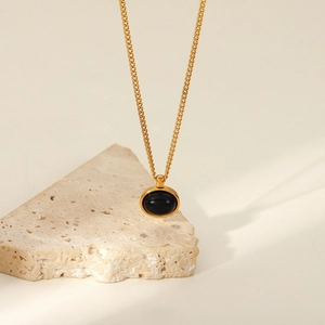 Detailed view of an oval black natural stone pendant on an 18K gold-plated stainless chain