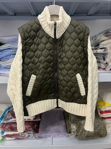 Detail of color-block jacket showing dark green quilted body and cream knit sleeves