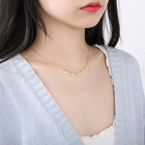 Close-up of a gold star and moon necklace on a woman's neck for a trendy minimalist look