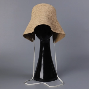 Detailed texture of natural raffia sun hat with white woven ribbon ties on a studio display