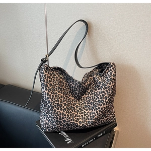 Close-up of leopard print tote bag on a black sofa with canvas fabric and slim strap