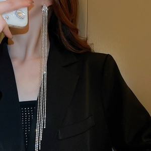 Dettaglio di orecchini lunghi con nappe d'argento e strass indossati da una modella