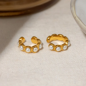 Macro shot of 18k gold stainless steel C-hoop clip-on earrings with white pearls on linen