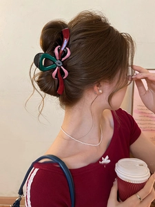 Détail de la pince à cheveux nœud bicolore sur chignon élégant avec finition résine brillante