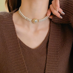 Close-up of double-layer pearl necklace with a gold oval diamond clasp on female model