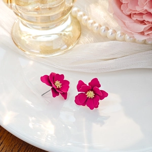 Detail of magenta layered flower earrings with golden matte stamens on white ceramic