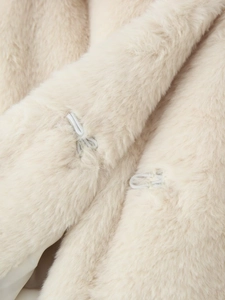 Close-up of invisible hook fasteners on soft cream faux fur coat with plush texture