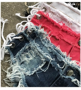 Dettaglio di pantaloncini in denim strappati con occhielli stringati e bordi sfilacciati
