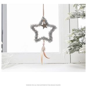 Detail of grey plush star ornament with small wooden star and soft feathers hanging on tree