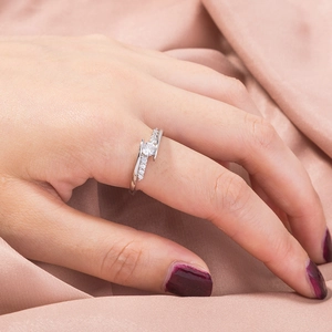 Elegant silver twisted band ring with round zircon gemstone on pink silk background