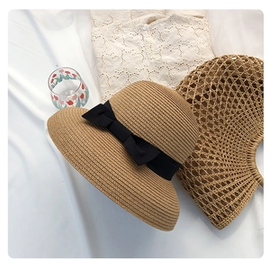 Detailed straw texture of khaki sun hat with elegant black ribbon bow decoration