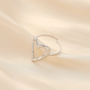 Elegant hammered silver heart ring with adjustable opening on luxury silk background