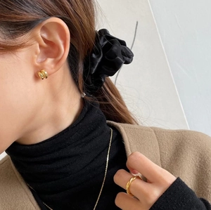Elegant gold hoop earrings and twisted ring set on model wearing black turtleneck