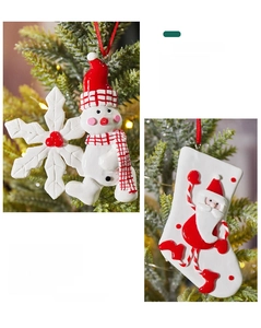 Detail of handmade clay snowman and Santa sock ornaments hanging on a Christmas tree