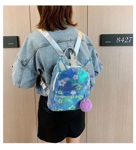 Rear view of a girl wearing a shiny sequin unicorn backpack with a purple pom-pom charm