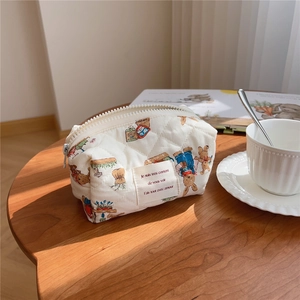 Quilted cotton cosmetic bag with bear print on a wooden table with coffee cup