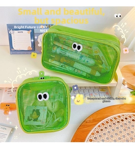 Detailed view of green mesh storage pouches with cartoon eyes on a desktop workspace