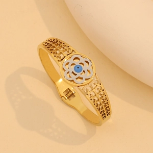 Dettaglio del bracciale rigido dorato con ciondolo occhio azzurro e cornice floreale