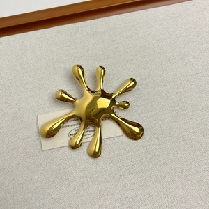Macro shot of gold liquid fluid brooch on a rustic linen cloth and wood background