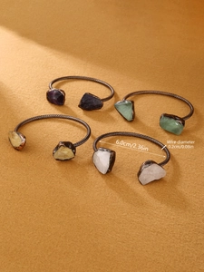 Detail of vintage bronze wire cuff bracelets with colorful natural raw gemstones
