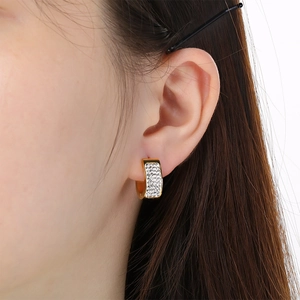 Detailed close-up of a gold U-shaped earring with dense pave-set white cubic zirconia stones