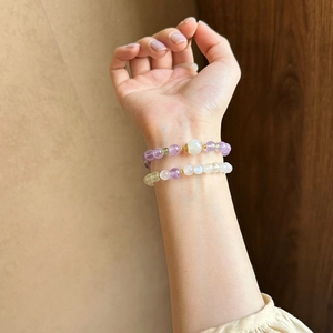 Detailed close-up of stacked purple and green amethyst beaded bracelets with gold accents