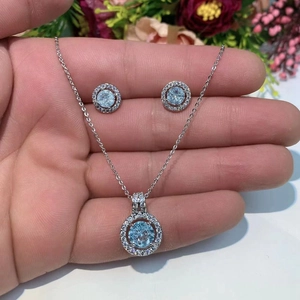 Detailed view of silver necklace and earrings set with light blue round zircon stones