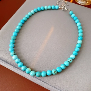 Detail view of turquoise bead necklace with natural texture and silver metal clasp
