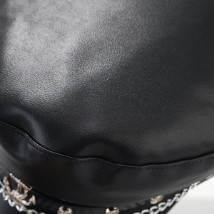 Dettaglio della texture in pelle nera con catena in metallo argentato e ancora sul cappello