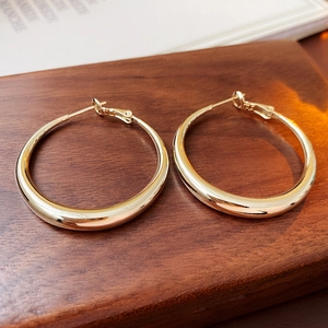 Close-up of elegant gold hoop earrings on dark wood surface with luxury feel