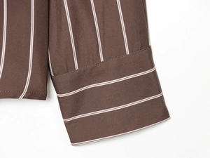 Detailed macro view of striped shirt cuff featuring precision stitching and brown white patterns