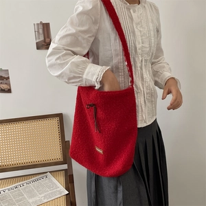 Detalle de bolso tote de felpa roja con cordón de cuero llevado por una modelo real