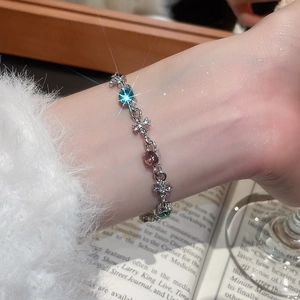 Detailed view of silver cross bracelet with vibrant blue, purple, and green round crystals