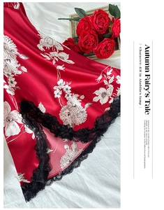 Dettaglio di camicia da notte in seta rossa con fiori bianchi e bordo in pizzo nero