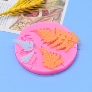 Pink silicone mold for tropical fern leaves fondant cake decoration on blue background