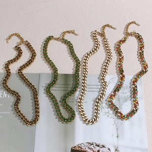 Detail of colorful enamel Cuban chain necklaces in gold-tone finish on a magazine